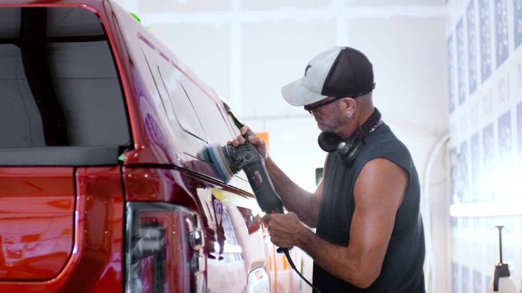 Employee buffing out red SUV